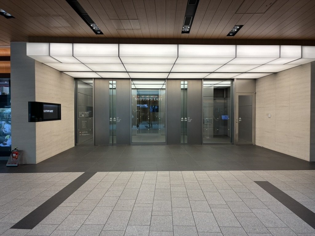地下1階の「MIDTOWN EAST」入口。ガラス扉の上に白い照明天井があります